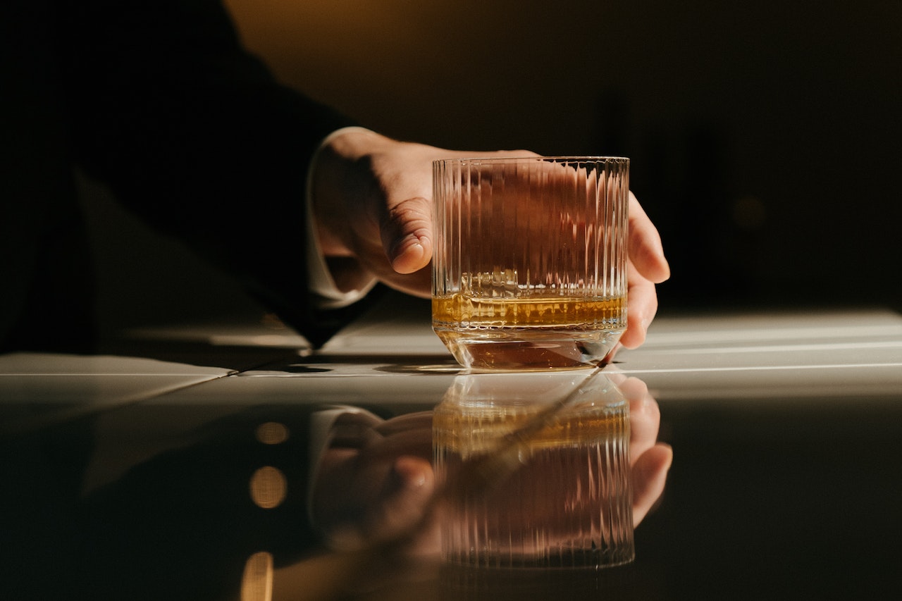 man holding a glass with whiskey